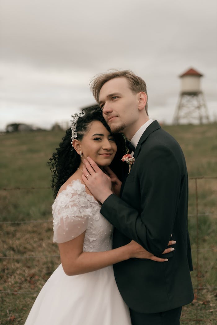 about-01 Bride and groom embrace in front of a historic tower in a pastoral setting.
