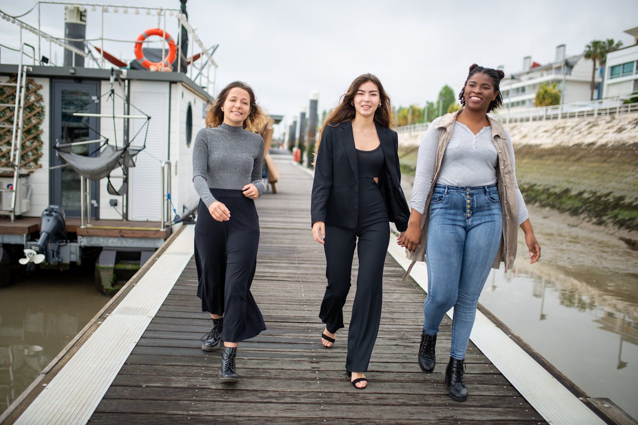 hero-img-02 Three young women happily walking on a pier in Portugal, enjoying a moment of friendship and joy.